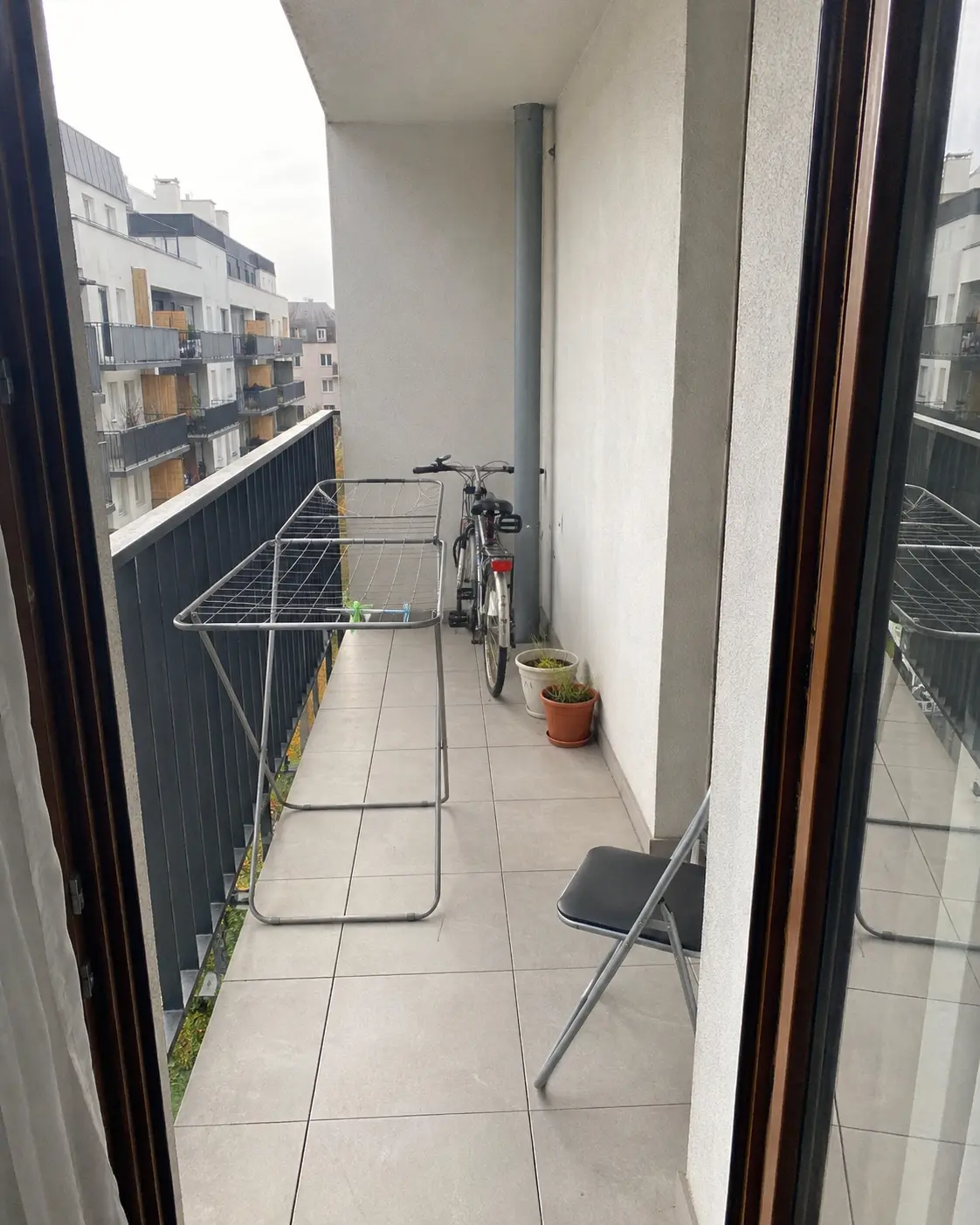 Wąski balkon przed zmianą — suszarka, rower i przypadkowe donice
