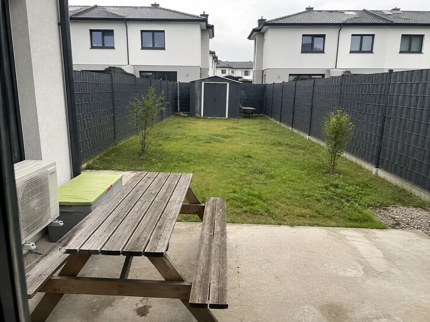 Ogród 118 m² przed projektem — surowy taras, trawnik i schowek